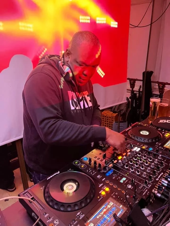 DJ Franco mixing music at the decks under red stage lighting