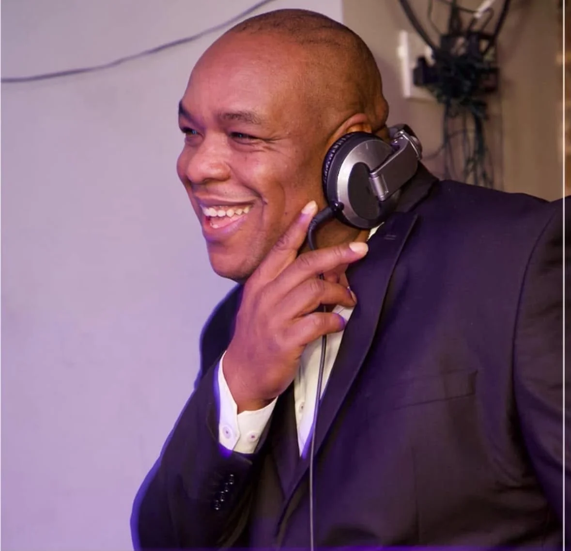 DJ Franco smiling in a suit with headphones